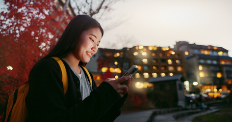 Happy asian woman, phone and night at city for social media, communication or outdoor networking. Female person smile on mobile smartphone in late evening for online chatting in urban town of Japan