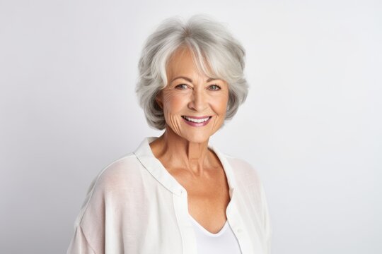Portrait of a happy senior woman smiling at the camera on grey background