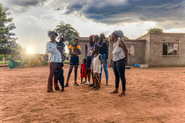 african family in the village enjoying the sunset in the yard after a good rain