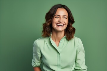 Portrait of a happy woman smiling and looking at camera against green background