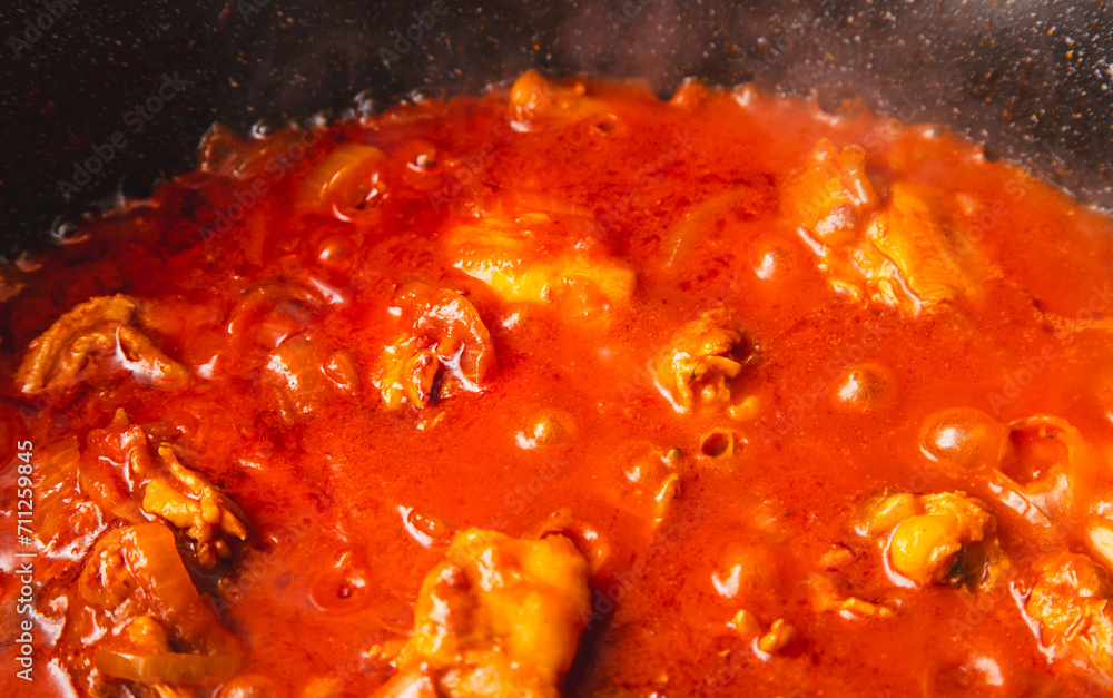 Wall mural chicken meat is stewed in tomato in a frying pan