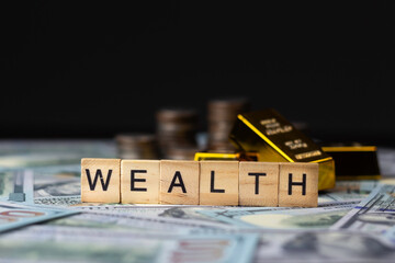 Wealth text on wooden blocks placed on banknotes With gold bars and piles of coins in the...