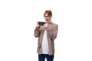 young handsome red-haired guy in a plaid shirt plays on the phone