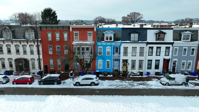 Snow covered colorful row houses and parked cars on a clear winter day. Aerial truck shot of urban housing after snow storm.