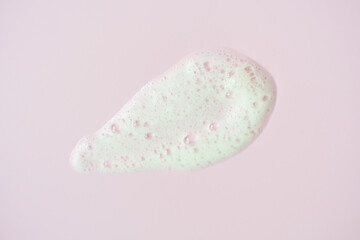 Smear of facial cleansing foam on pink background close-up.