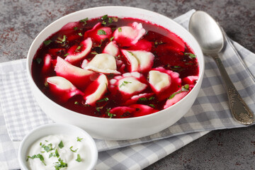 Old Polish beetroot borscht with traditional uszka dumplings stuffed with cabbage and mushrooms close-up in a bowl on the table. Horizontal
