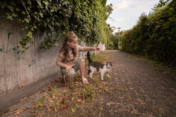 Obraz premium Teen girl plays with a cat, outdoors, village