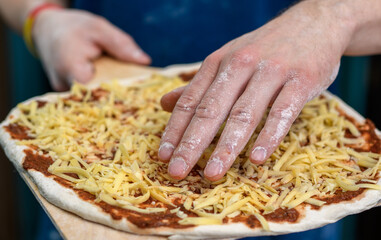Pizza margherita w trakcie przygotowania, surowy placek z sosem i serem przed włożeniem do pieca - obrazy, fototapety, plakaty