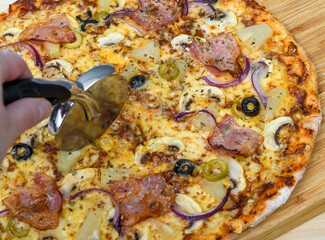 Okrągła pizza krojona nożem do pizzy z bliska