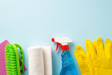 Embrace cleanliness with household items. Top-down view of cleaning supplies—brush, gloves, spray, rugs—on a muted blue background. Perfect for text or promotions - obrazy, fototapety, plakaty