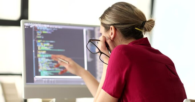Woman programmer with glasses in hand studying information on computer screen 4k movie slow motion. It development of computer programs concept