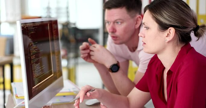 Male and female programmers discussing information on computer screen 4k movie slow motion. Help colleagues and teamwork in business concept