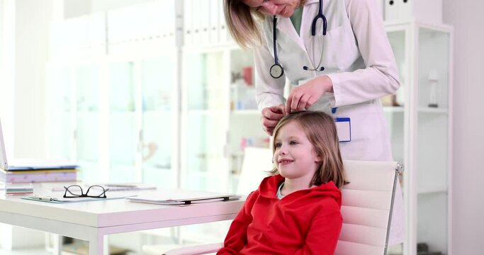 Doctor pediatrician examining head and hair of child in clinic 4k movie slow motion. Diagnosis and treatment of pediculosis and microsporia concept