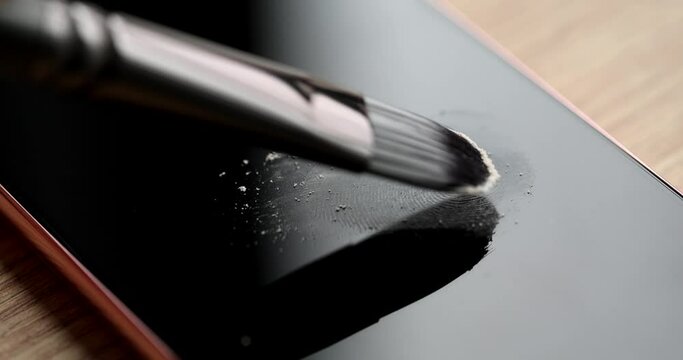 Forensic expert brushing talcum powder on fingerprint on mobile phone screen closeup 4k movie slow motion. Traces of crime disclosure of criminal cases concept