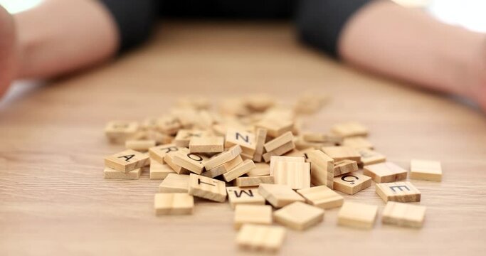 Hands pouring on table lot of wooden cubes with letters of alphabet closeup 4k movie slow motion. Board games concept