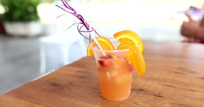 Orange cocktail with straw and slice of orange and strawberries on sea beach. Summer delicious cold vitamin cocktail