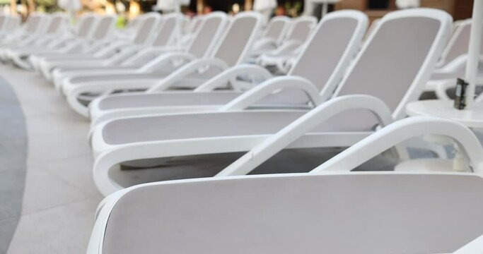 Stylish white sun loungers by pool on sunny day. Selection of quality summer sun loungers