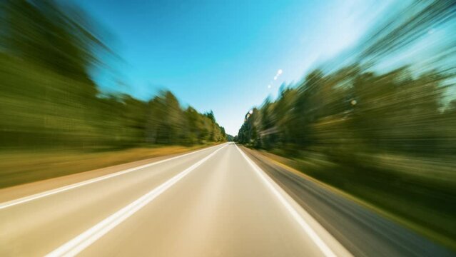 Hyperlapse Point of View Driving on the Highway Outside the City. A Car Moves Fast Along the Country Road on a Sunny Day. Trees Turning Into Abstract Blur. Hyperlapse