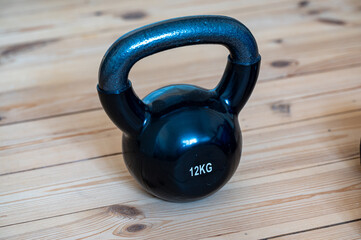 One kettlebell of 12 kg standing on wooden floor at home