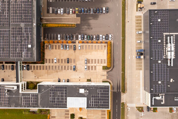 Drone photography of logistical warehouse with solar panels on the roof and parking place for cars during autumn morning
