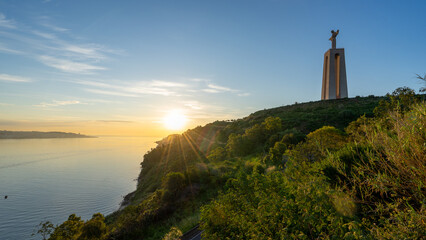 statue of Christ in Almada/Lisbon, with the morning sun falling on the tarred road and the Tagus...