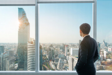 A businessman is observing the future metropolis from the top of an office tower.