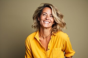 Portrait of a smiling mature woman in yellow shirt over grey background