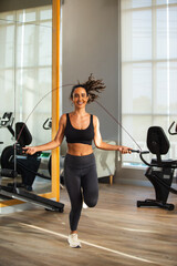 woman sportwear jump rope exercise in gym health club. sportswoman slim motivation jump rope calories burn.