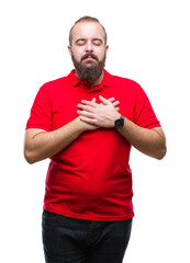 Young caucasian hipster man wearing red shirt over isolated background smiling with hands on chest with closed eyes and grateful gesture on face. Health concept.