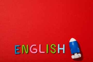 The word English with a rocket next to it, on a red background. - obrazy, fototapety, plakaty
