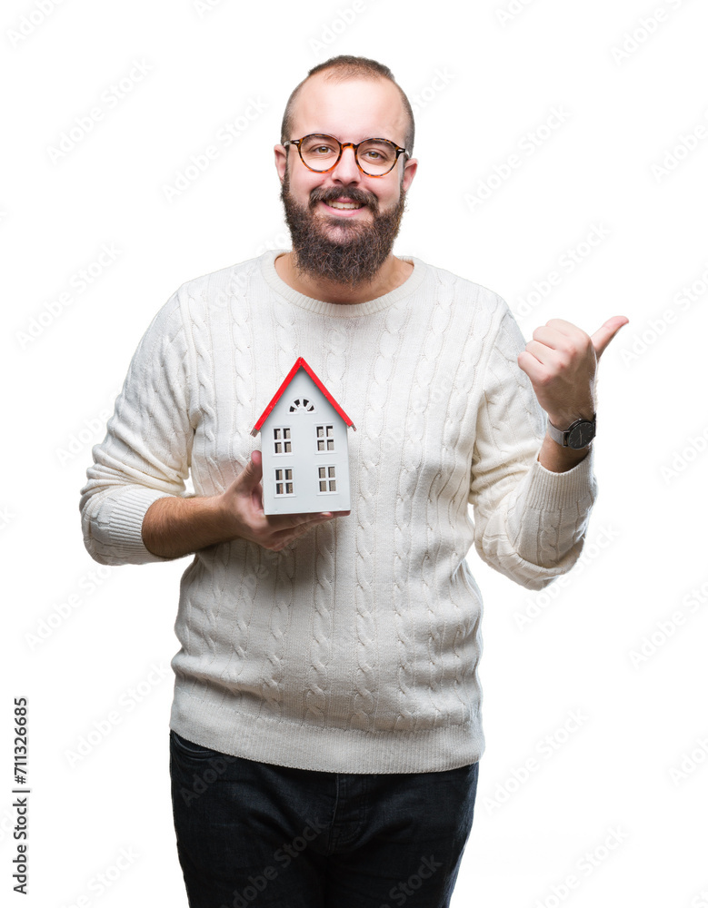 Sticker young caucasian real state agent man holding house isolated background pointing and showing with thu