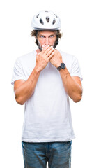 Handsome hispanic cyclist man wearing safety helmet over isolated background shocked covering mouth with hands for mistake. Secret concept.