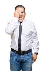 Middle age bussines arab man wearing glasses over isolated background covering one eye with hand with confident smile on face and surprise emotion.