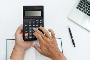 Hand of Accountant using a calculator with a computer laptop and pen concept finance tax. Top view table