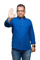 Middle age arab man wearing glasses over isolated background doing stop sing with palm of the hand. Warning expression with negative and serious gesture on the face.