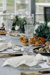 Classy table with a bouquet. Luxury dining set with cutlery, serviette, crockery and covered with a tablecloth in restaurant.