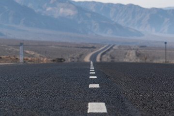 Fototapeta premium Empty asphalt road stretching beyond the horizon. Endless mountain road. Concept of road travel in Central Asia. Selective focus.