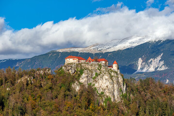 Fototapeta na wymiar Castle on cliff with mountains as backdrop in Bled, Slovenia