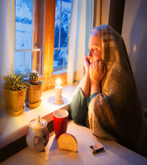 Woman warming herself by a candle in blackout