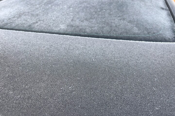 A Car Covered in Frost on a Cold Winter Morning.Patterns of ice crystals on the surface of the vehicle. The dew drops add some sparkle to the frozen scene. The car is parked outdoors