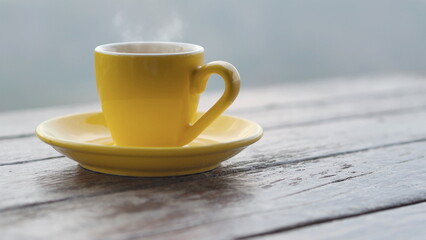 yellow coffee cup In the morning, a coffee cup is placed on the table in the background of a natural view.