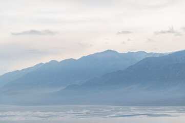 Bluish silhouettes of misty mountains and a panorama of the lake. Beautiful mountain landscape....