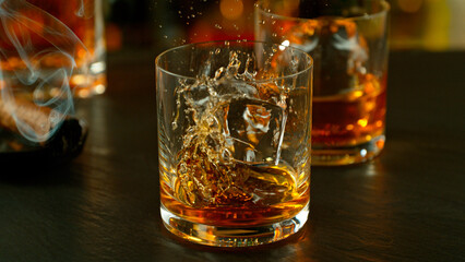 Close-up of pouring whiskey or rum on the bar, dark toned background