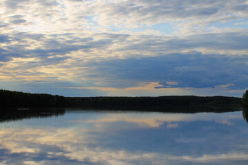 A smooth lake against the backdrop of a forest and sunset sky. Republic of Karelia. Russia.