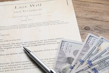 Last Will and Testament, dollar bills and pen on wooden table, closeup