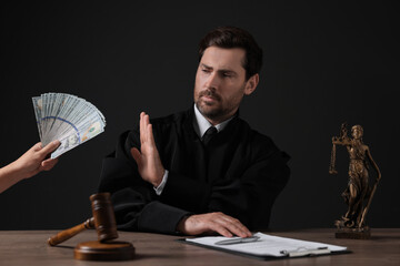Woman giving bribe to judge at wooden table against black background