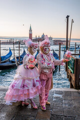 Colorful carnival masks at a traditional festival in Venice against gondolas, Italy