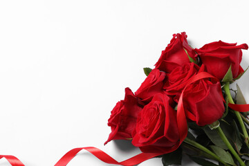 Beautiful red roses and ribbon on white background, top view. Space for text