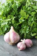 Fresh raw garlic and parsley on grey table, closeup