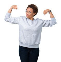 Young beautiful african american woman wearing glasses over isolated background showing arms muscles smiling proud. Fitness concept.